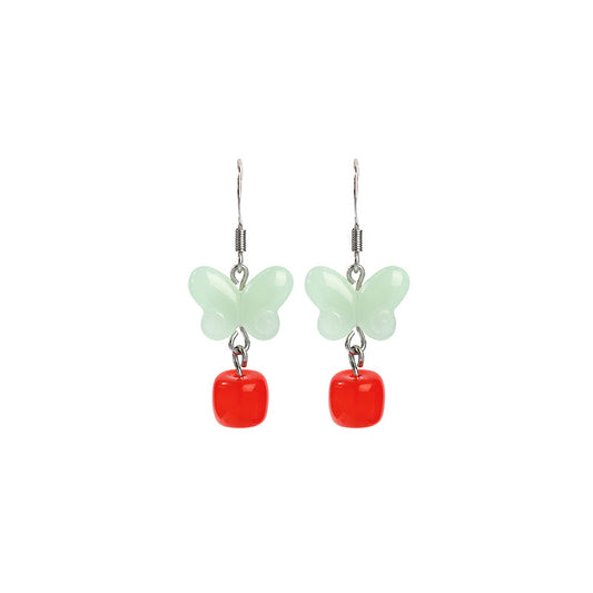 Pair of mint butterfly and red drop earrings on white