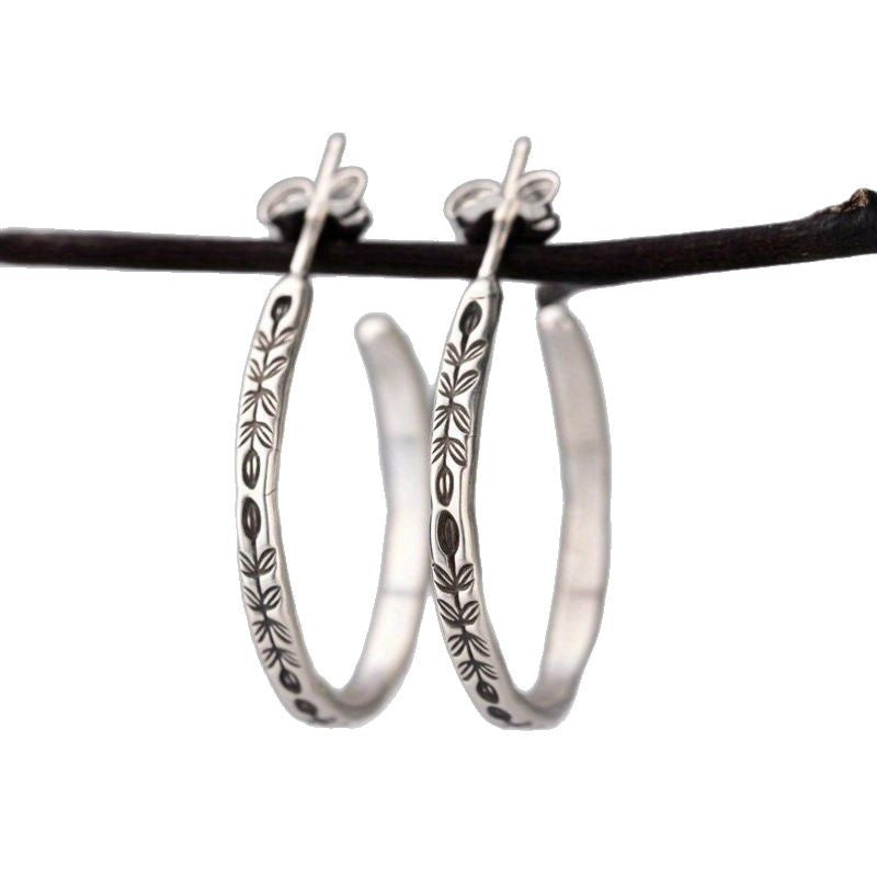 Silver-tone hoop earrings with engraved leaves and flowers on white