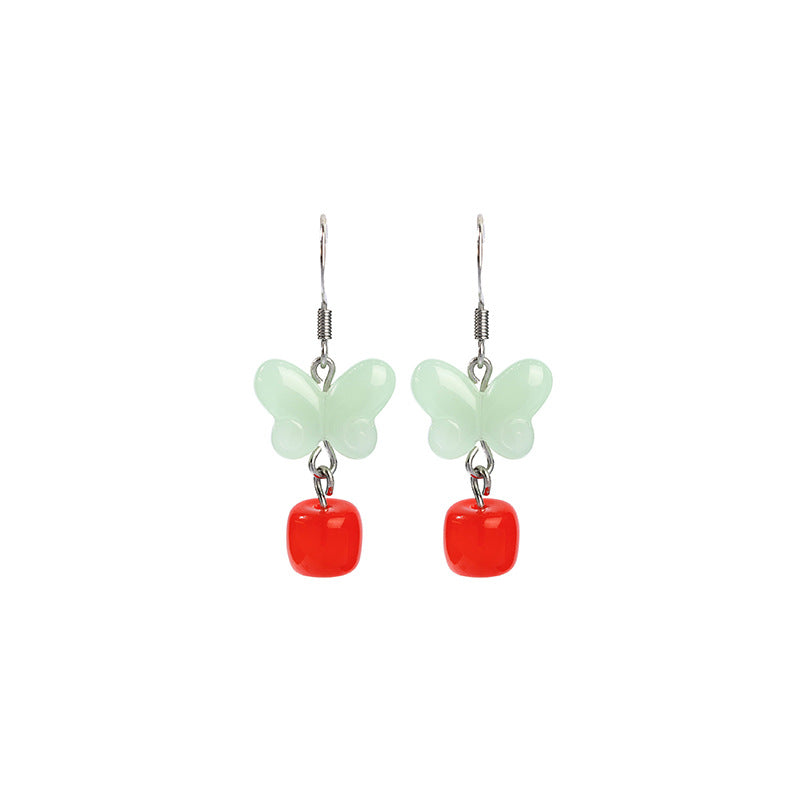 Pair of mint butterfly and red drop earrings on white