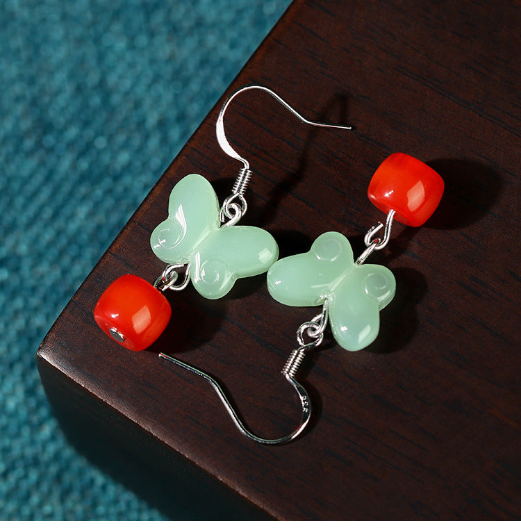 Close-up of the butterfly earrings on a dark wooden surface