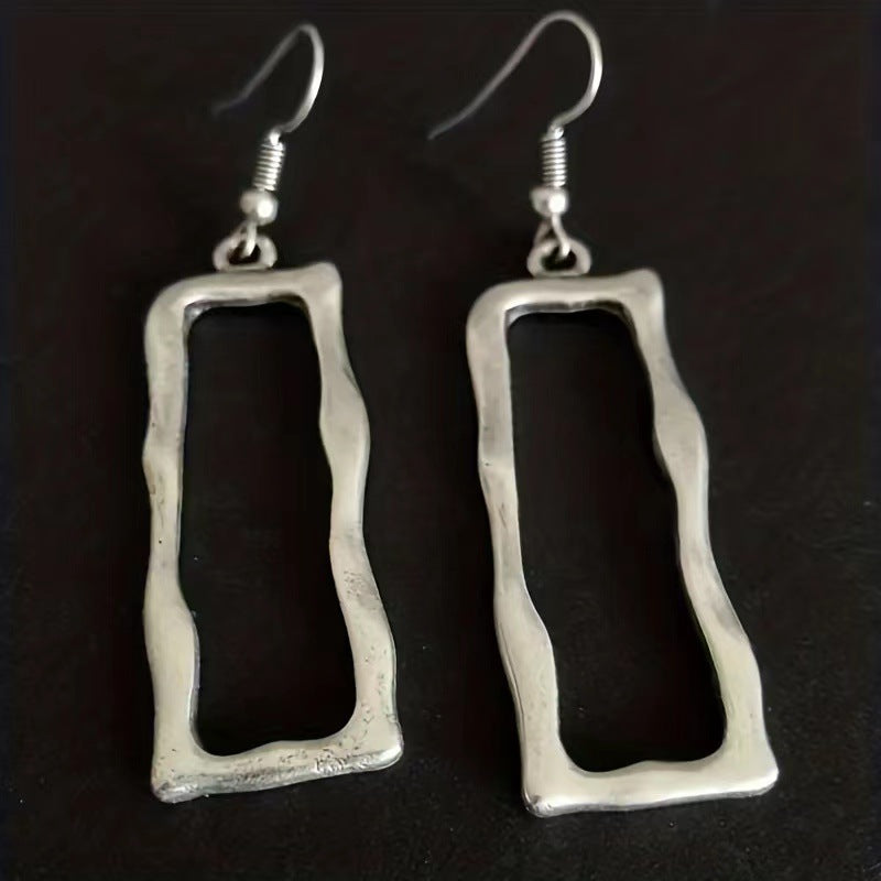 Pair of irregular open rectangle earrings on a dark background
