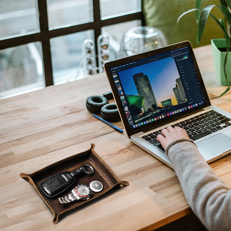 Brown valet tray beside a laptop on a wooden desk
