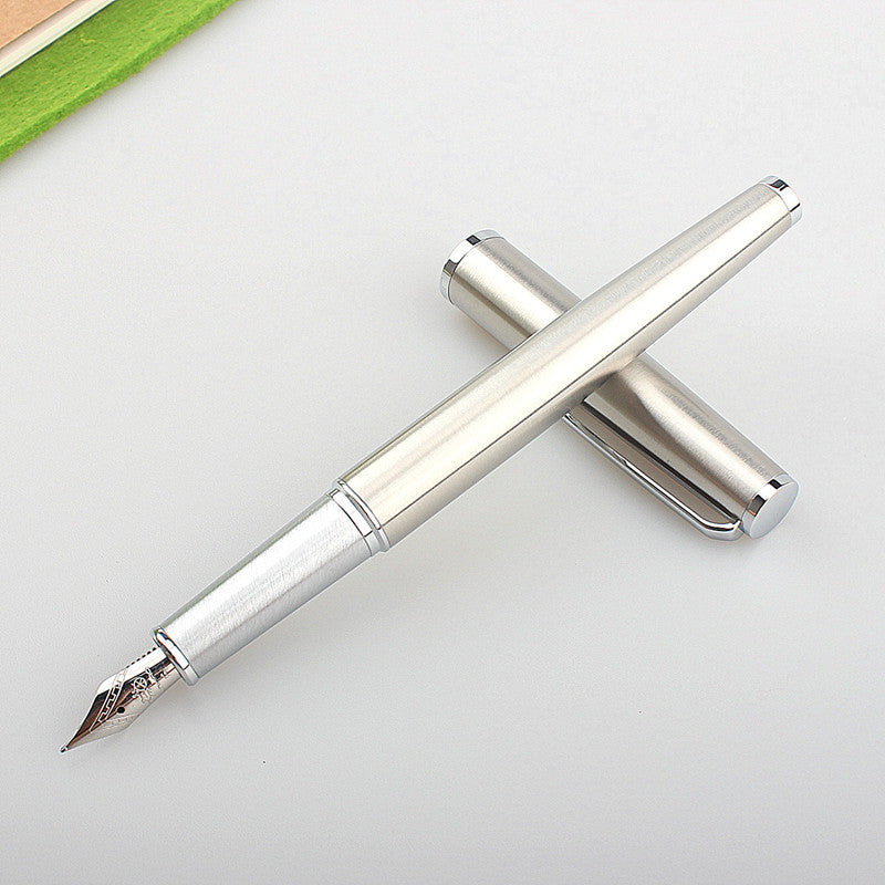 Silver fountain pen with cap removed on a light desk