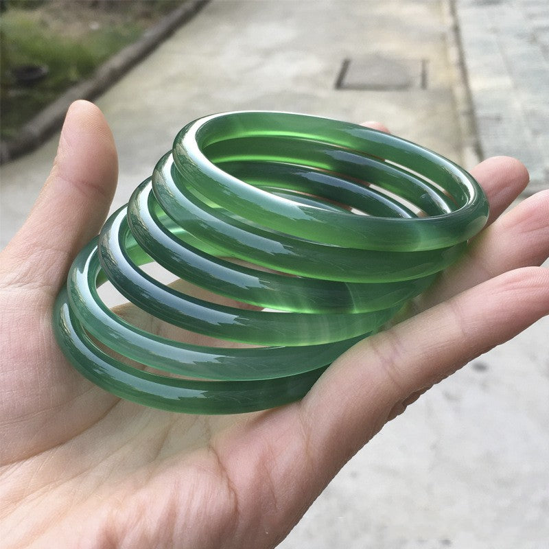 Several green translucent bangles held in a hand
