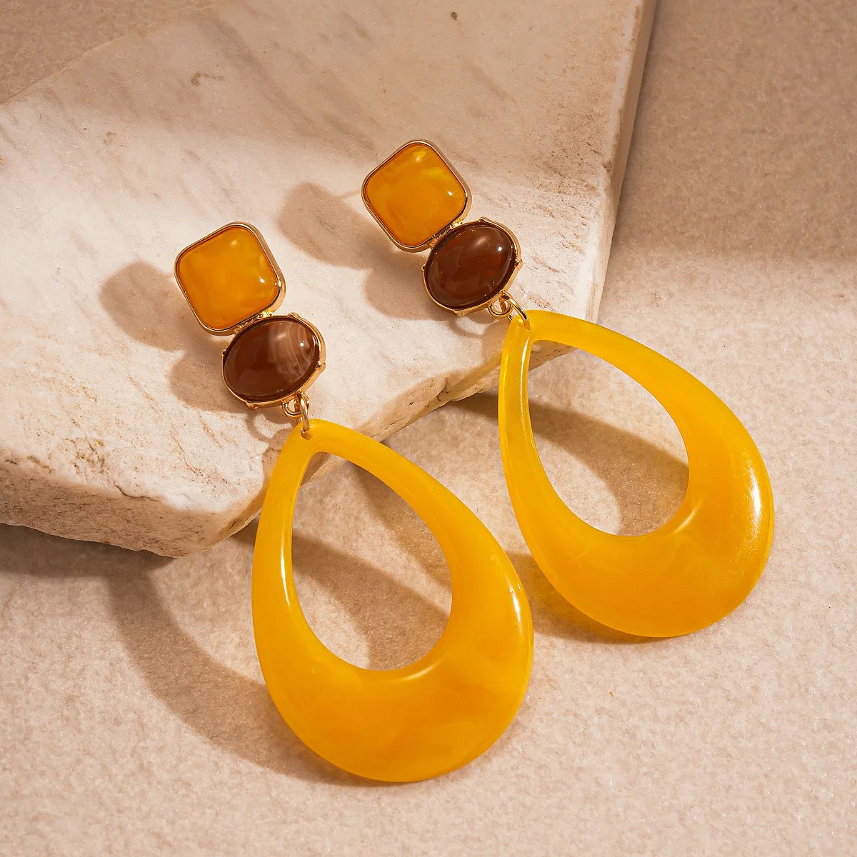 Pair of yellow resin teardrop earrings with amber square and brown round accents