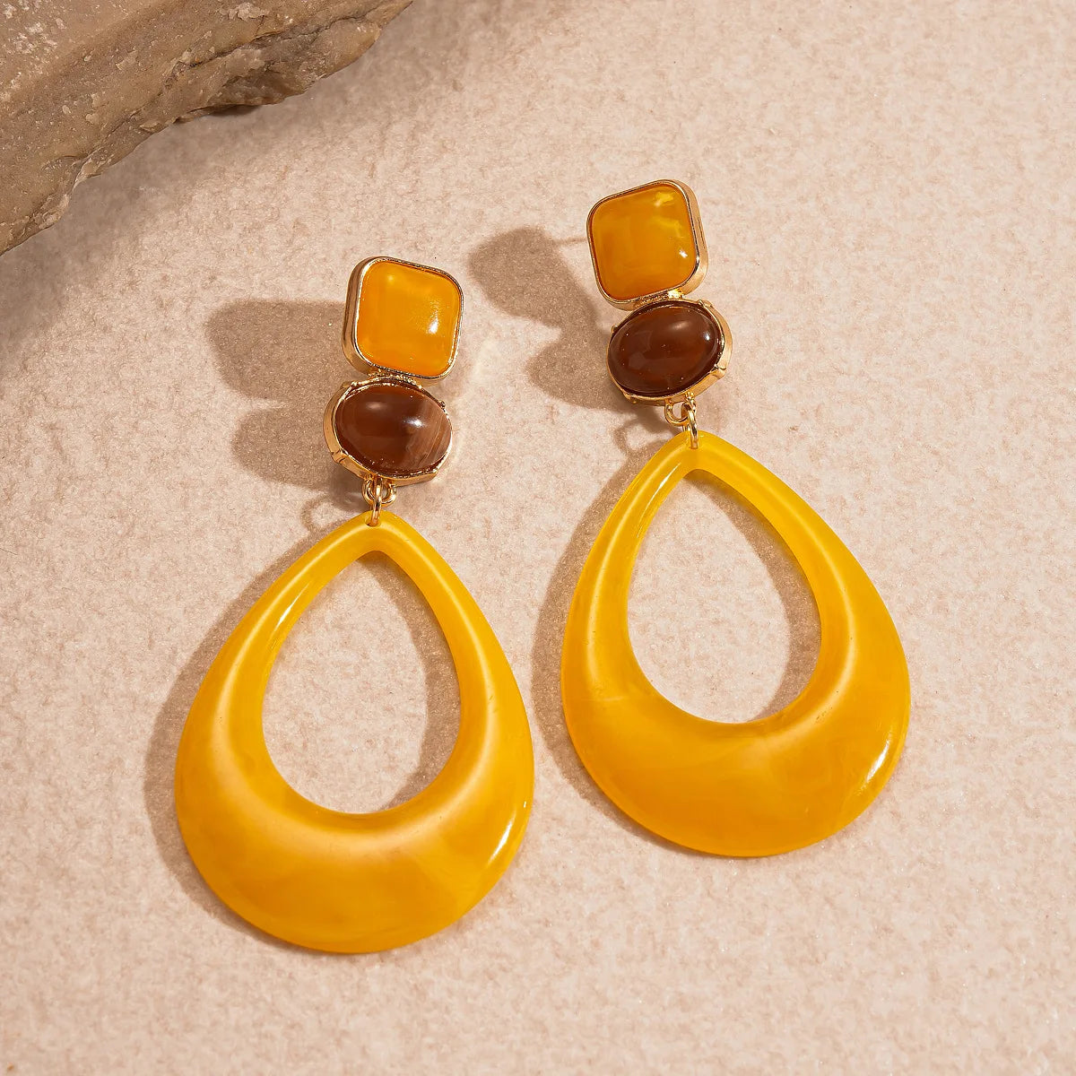 Pair of yellow resin teardrop earrings with amber and brown upper accents
