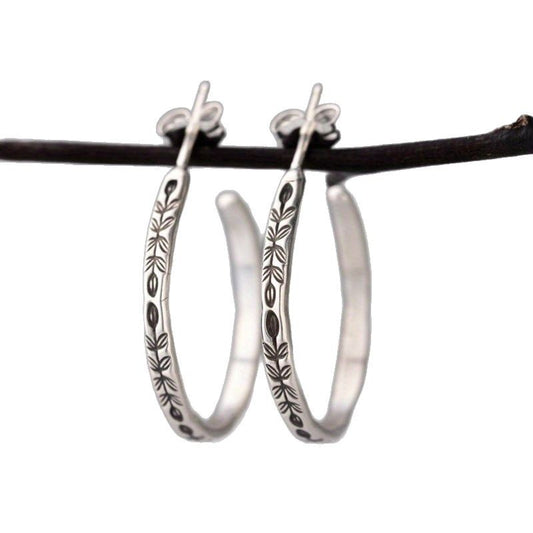Silver-tone hoop earrings with engraved leaves and flowers on white
